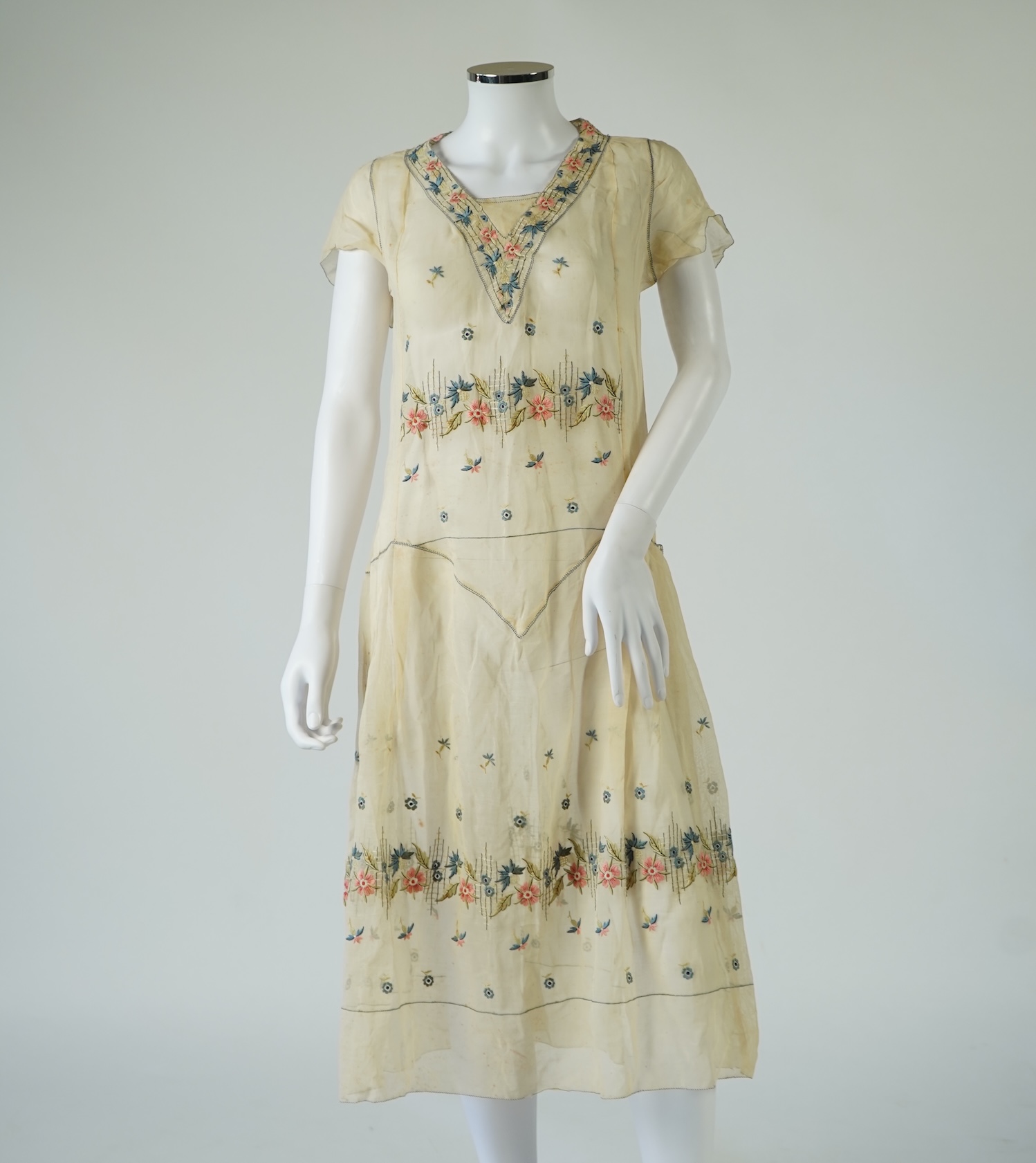 An unusual 1920's fine cream lawn summer dress with hand embroidered blue, pink, flowers, tie and picot edging., 116cm long. Condition - some small rust stains and one small tear at the back right shoulder.